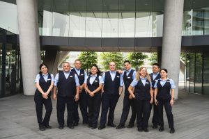 A team of uniformed cleaning staff stands proudly outside a modern building, ready for their duties.