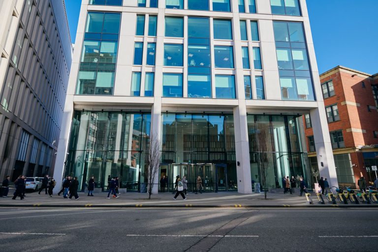 Modern building with glass facade, people walking by.